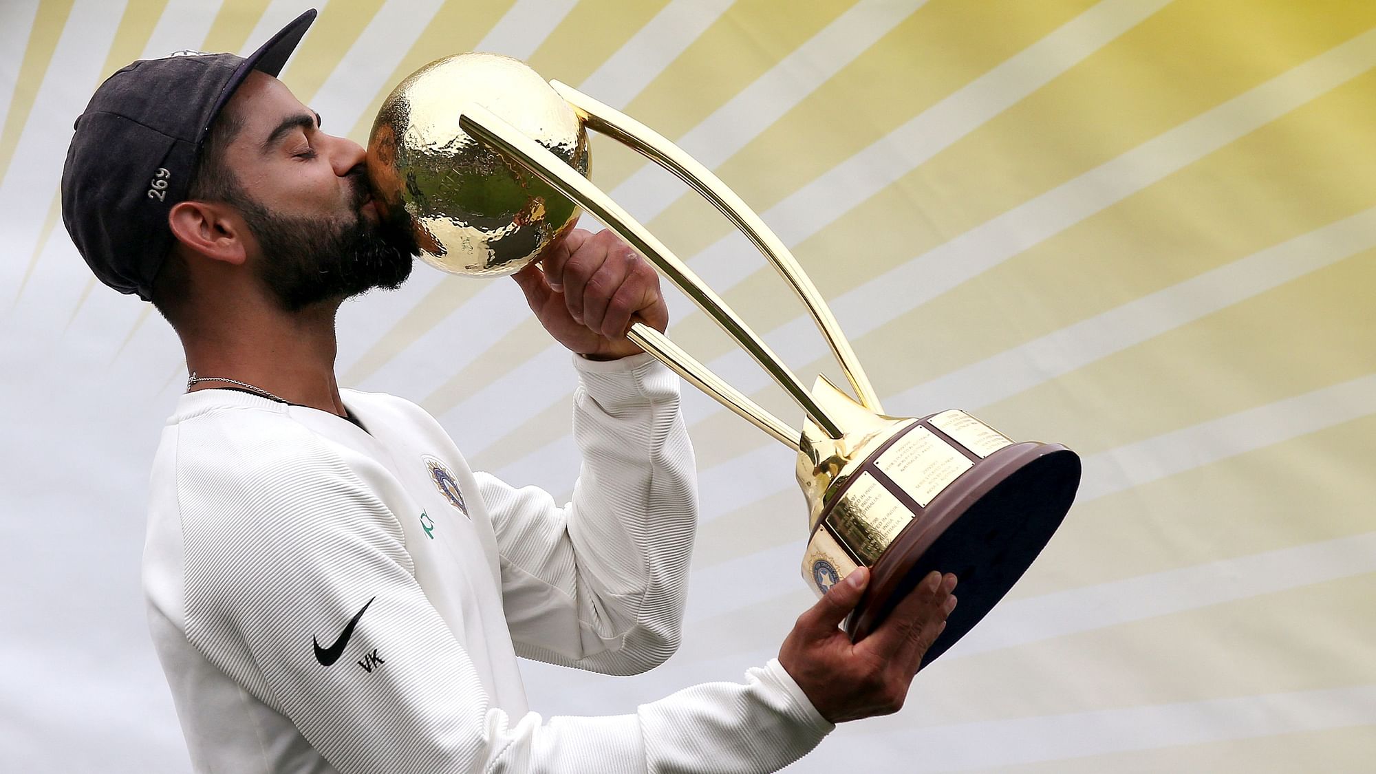 India’s Virat Kohli kisses the Border–Gavaskar Trophy as he celebrate their series win over Australia.