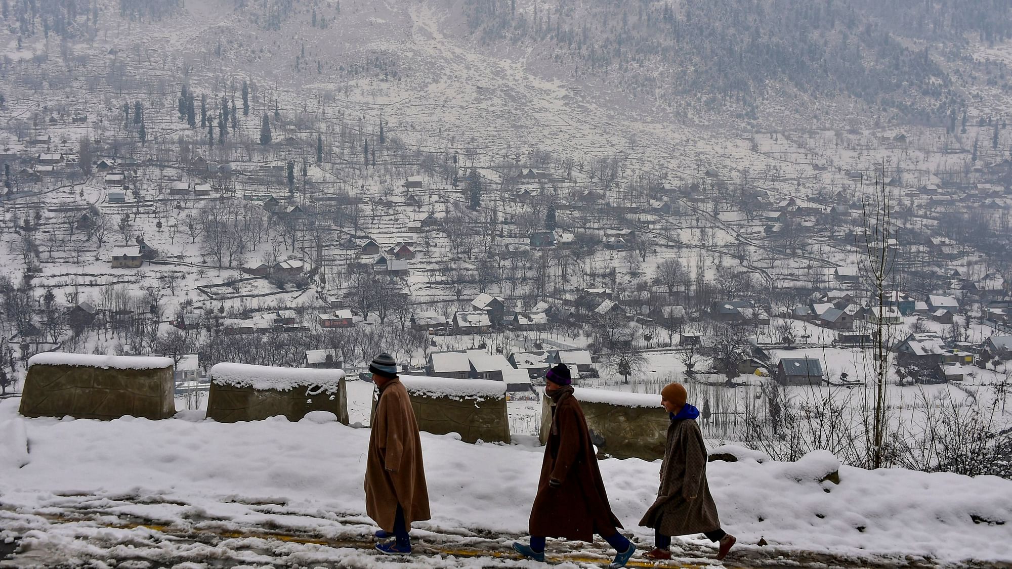 Boys walk down a snow-covered path at a village in Ganderbal district of central Kashmir on Wednesday, 2 January.&nbsp;