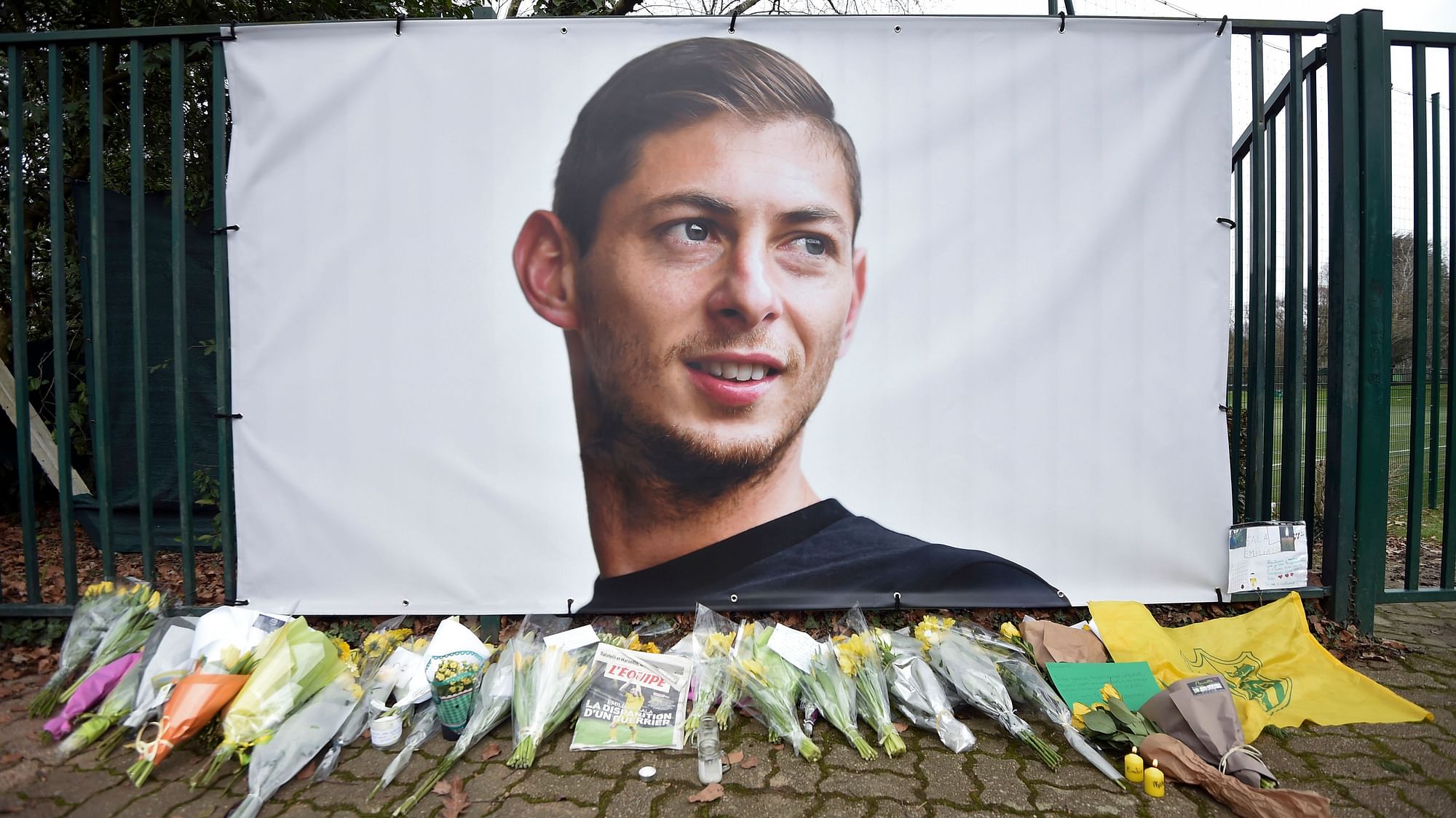 Flowers and tributes are placed near a giant picture of Argentine soccer player Emiliano Sala outside the FC Nantes training camp, in Nantes, western France, Thursday, Jan. 24, 2019, after a plane with Sala on board went missing over the English Channel on Monday night.