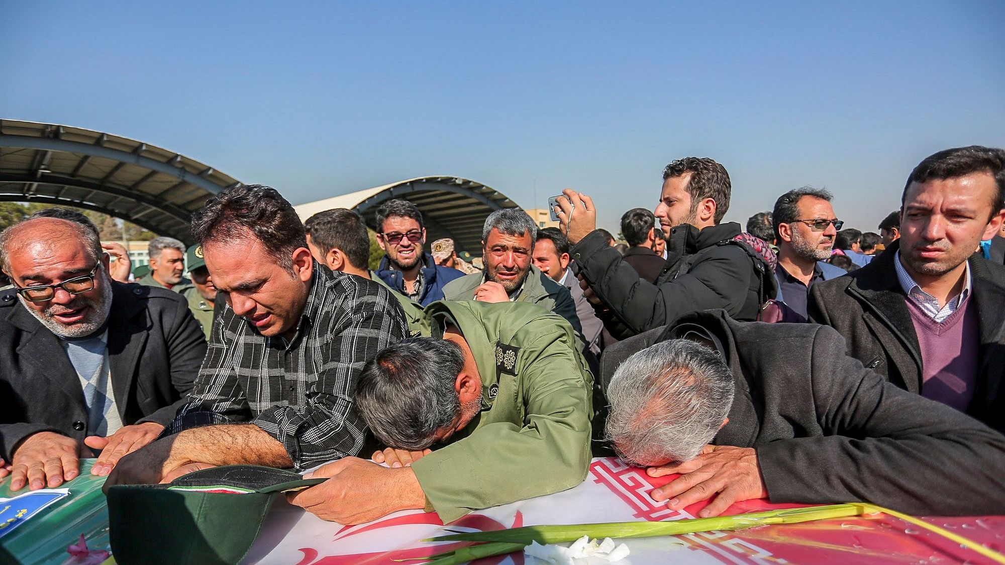In this photo provided by Tasnim News Agency, mourners weep over a flag-draped coffin of a member of Iran’s Revolutionary Guard who was killed in a suicide car bombing in Iran.