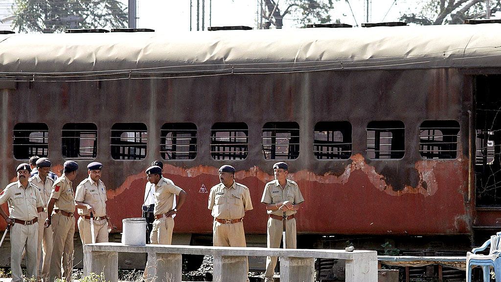 Police guard a coach that was set ablaze in Godhra in 2002.&nbsp;