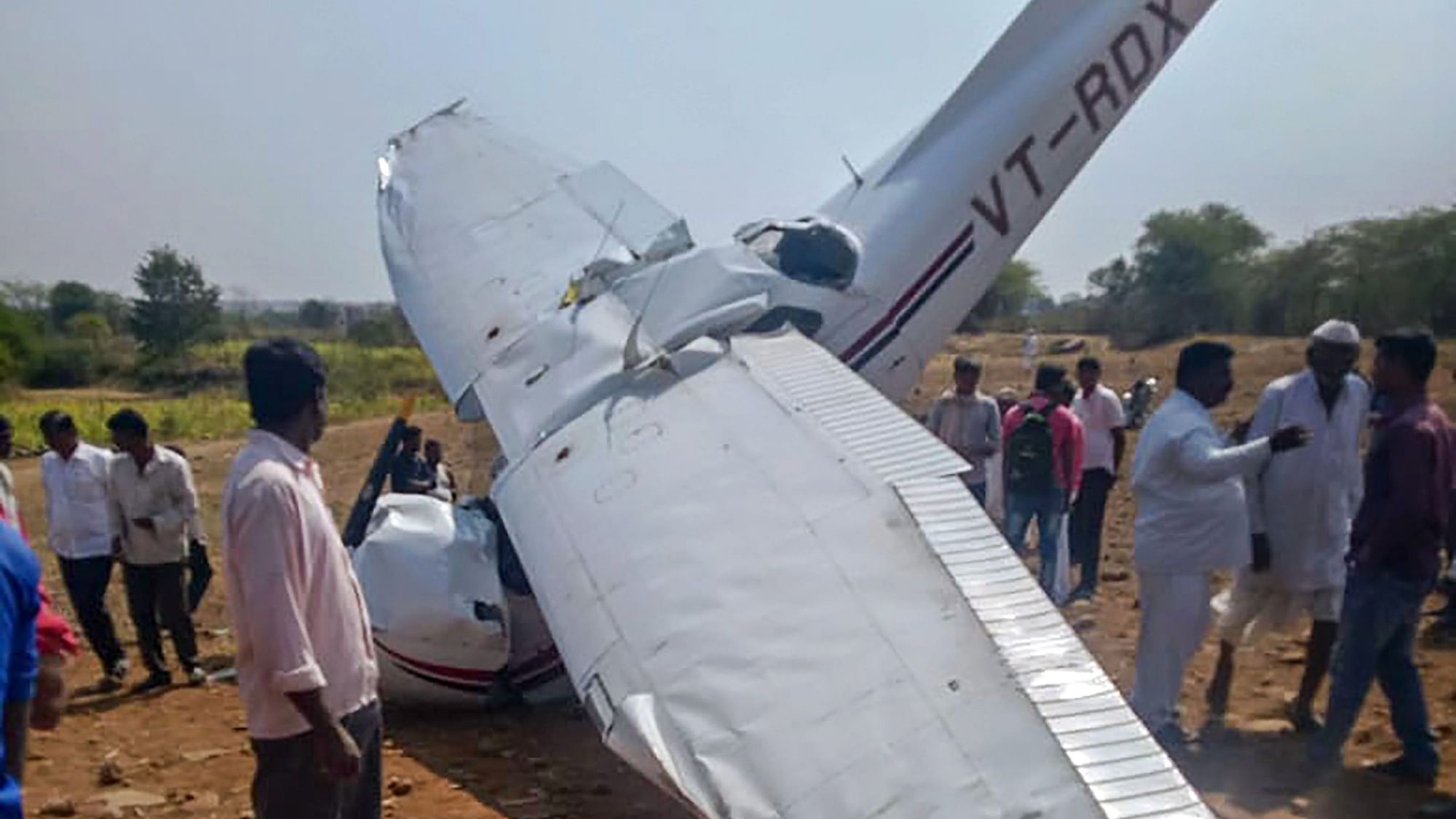  People inspect the wreckage of a crashed aircraft being used for civil aviation training in Pune district.