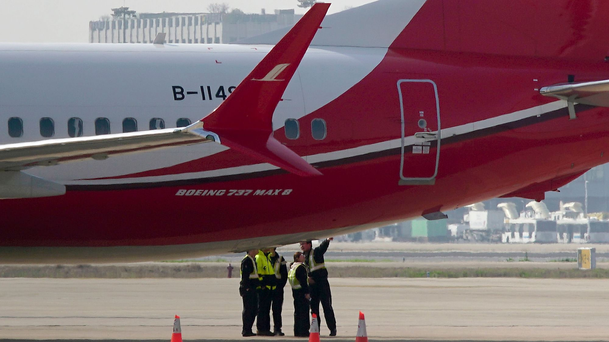 Ground crew chat near a Boeing 737 MAX 8 plane.