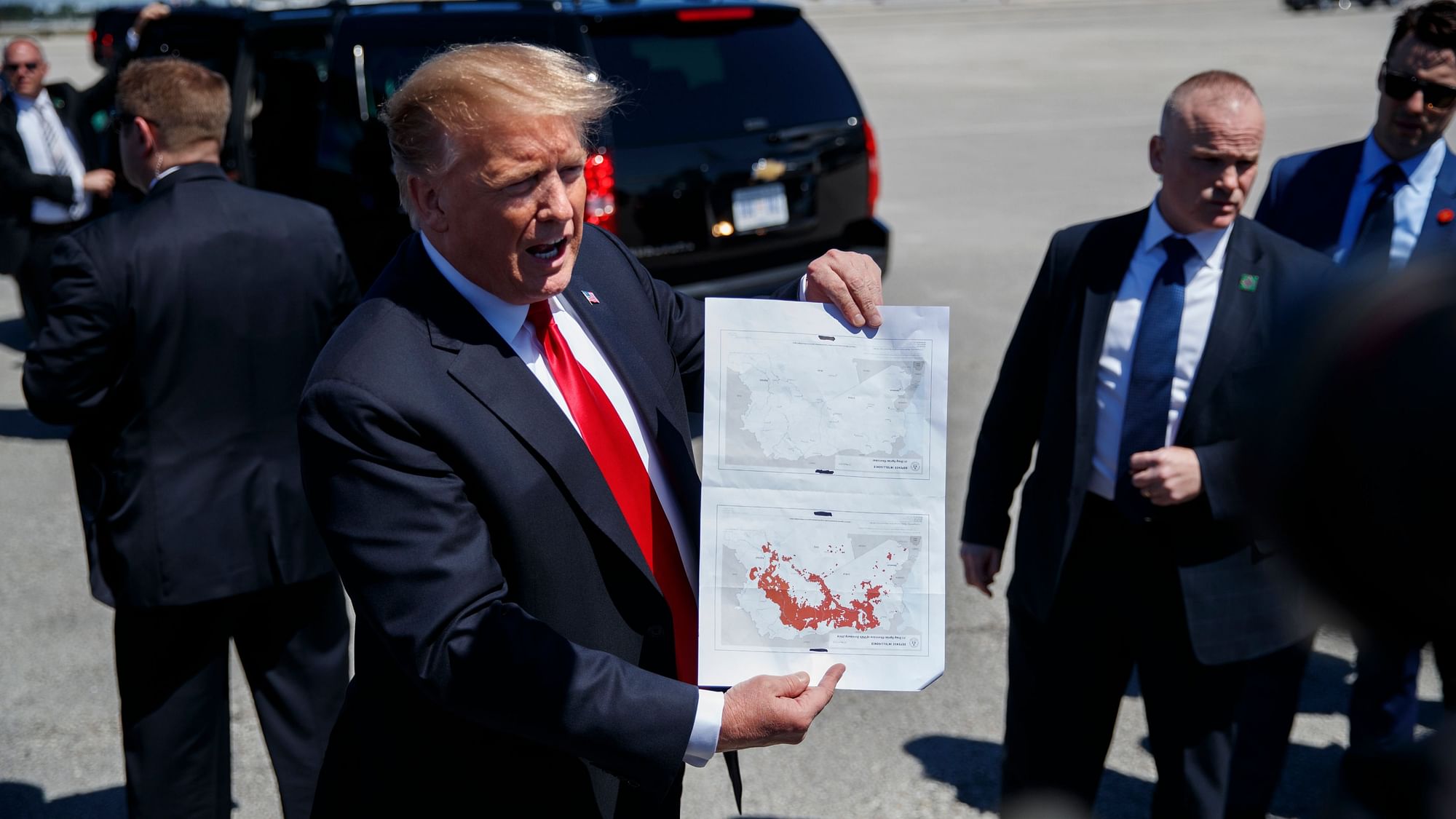 US President Donald Trump holds a copy of two maps of Syria, indicating that IS as of today no longer controls territory in the war-torn country.
