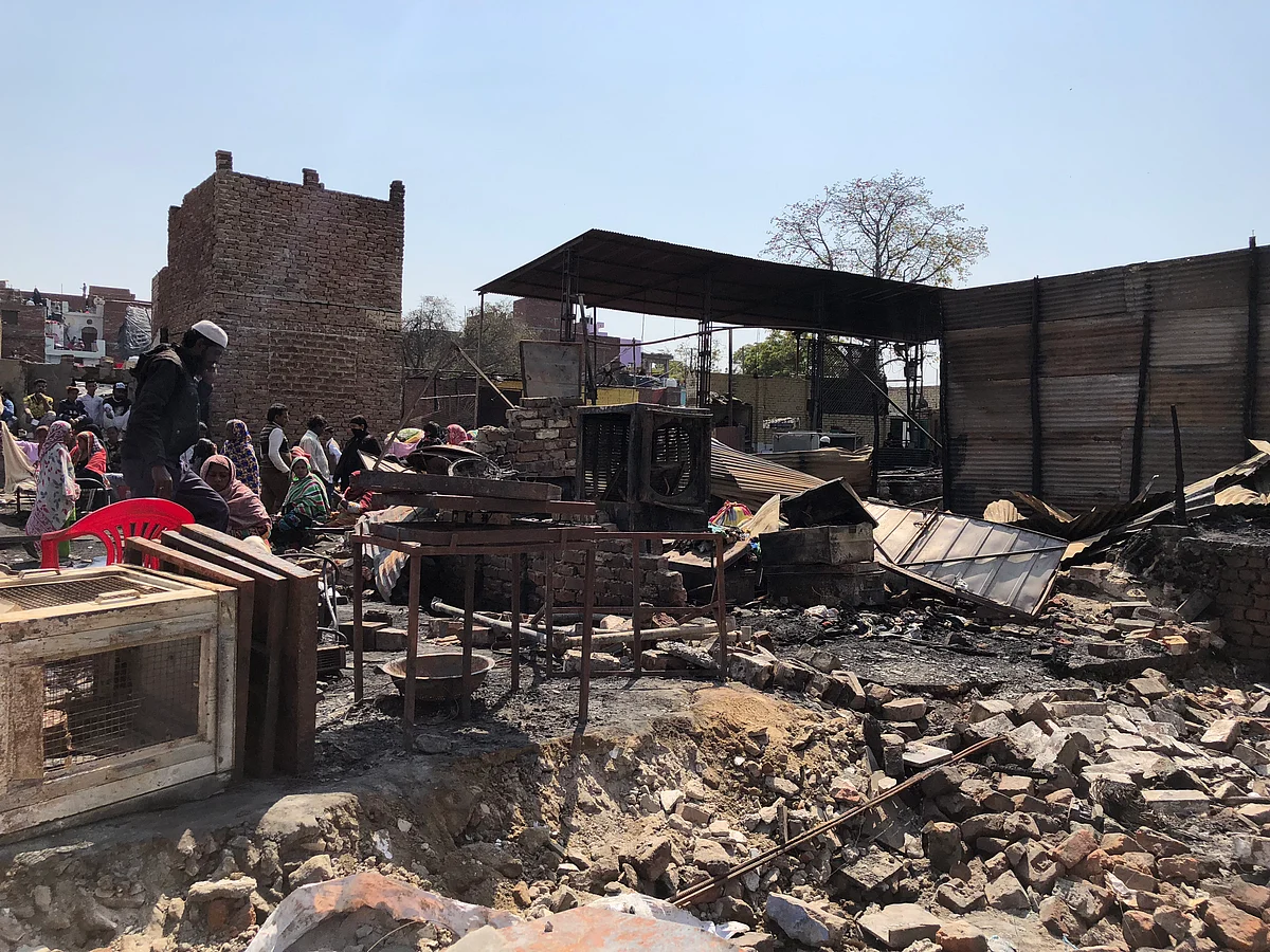 Slum residents sit amidst rubble.