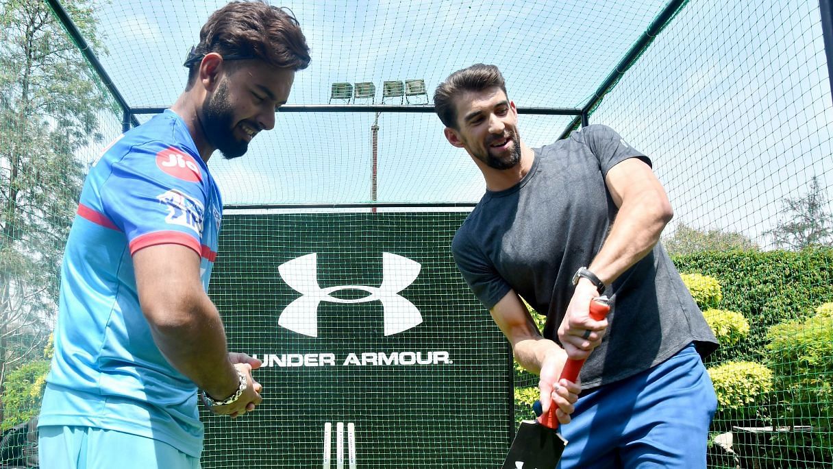 Indian cricketer Rishabh Pant shows Michael Phelps how to swing a bat.