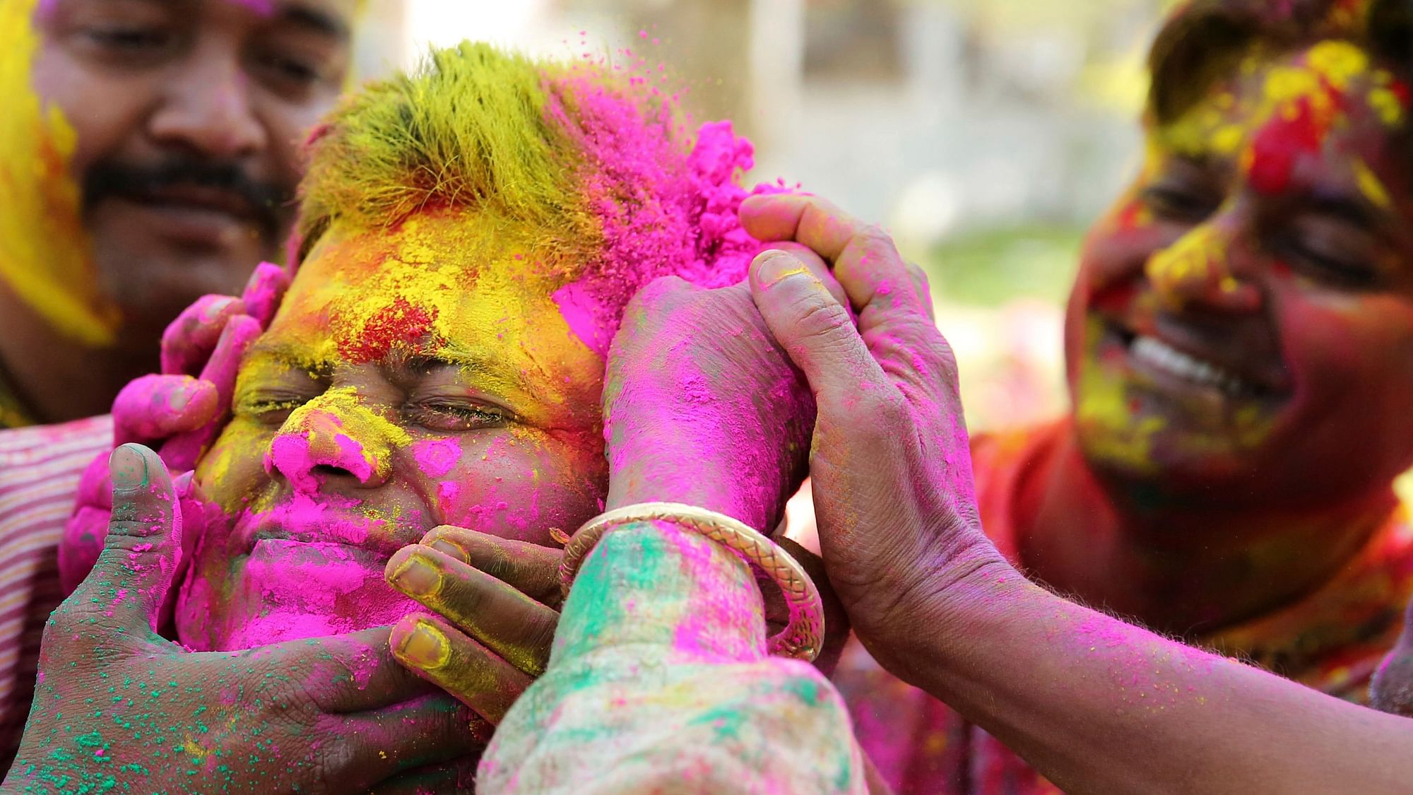 People smudge colour on each other while playing Holi.