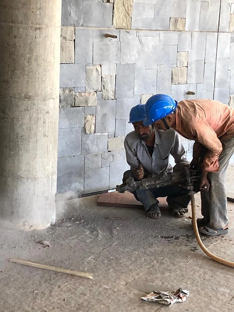 Workers drill holes into the pillar to plant the dynamites.