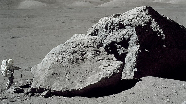 Apollo 17 astronaut Harrison H Schmitt standing beside a boulder on the lunar surface.