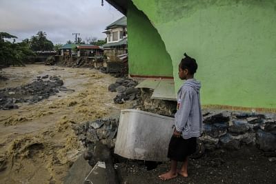 Sentani, March 17, 2019 (Xinhua) A girl stands near a collapsed building after flash floods in Sentani, Indonesia, on March 17, 2019. Sixty-three bodies have been retrieved after flash floods hit Indonesia