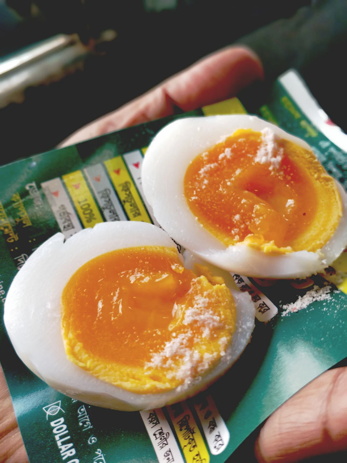 The man peels the eggs swiftly, places each on a piece of paper, slices it with a thread and sprinkles some rock salt.