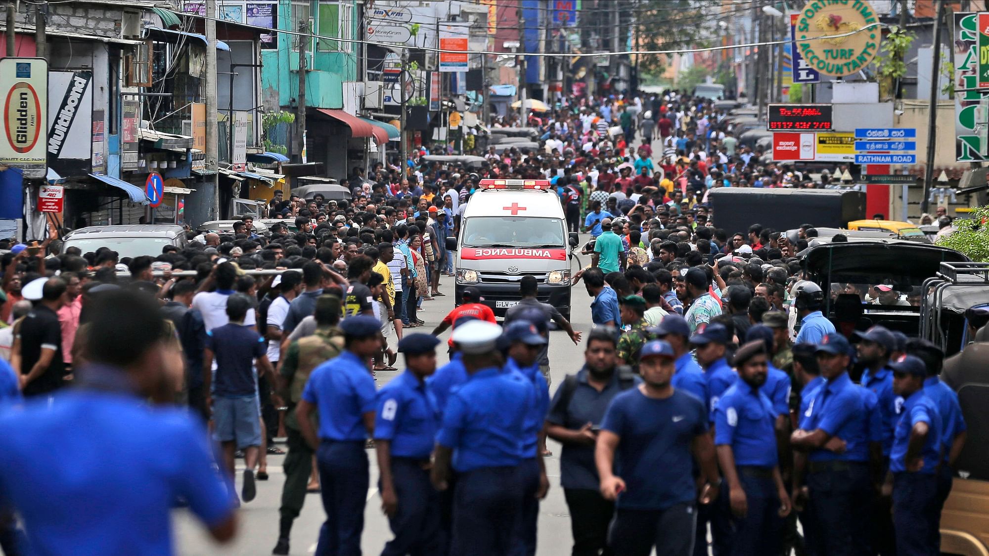 Sri Lankan police officers clear the road as an ambulance drives through carrying injured of Church blasts in Colombo.