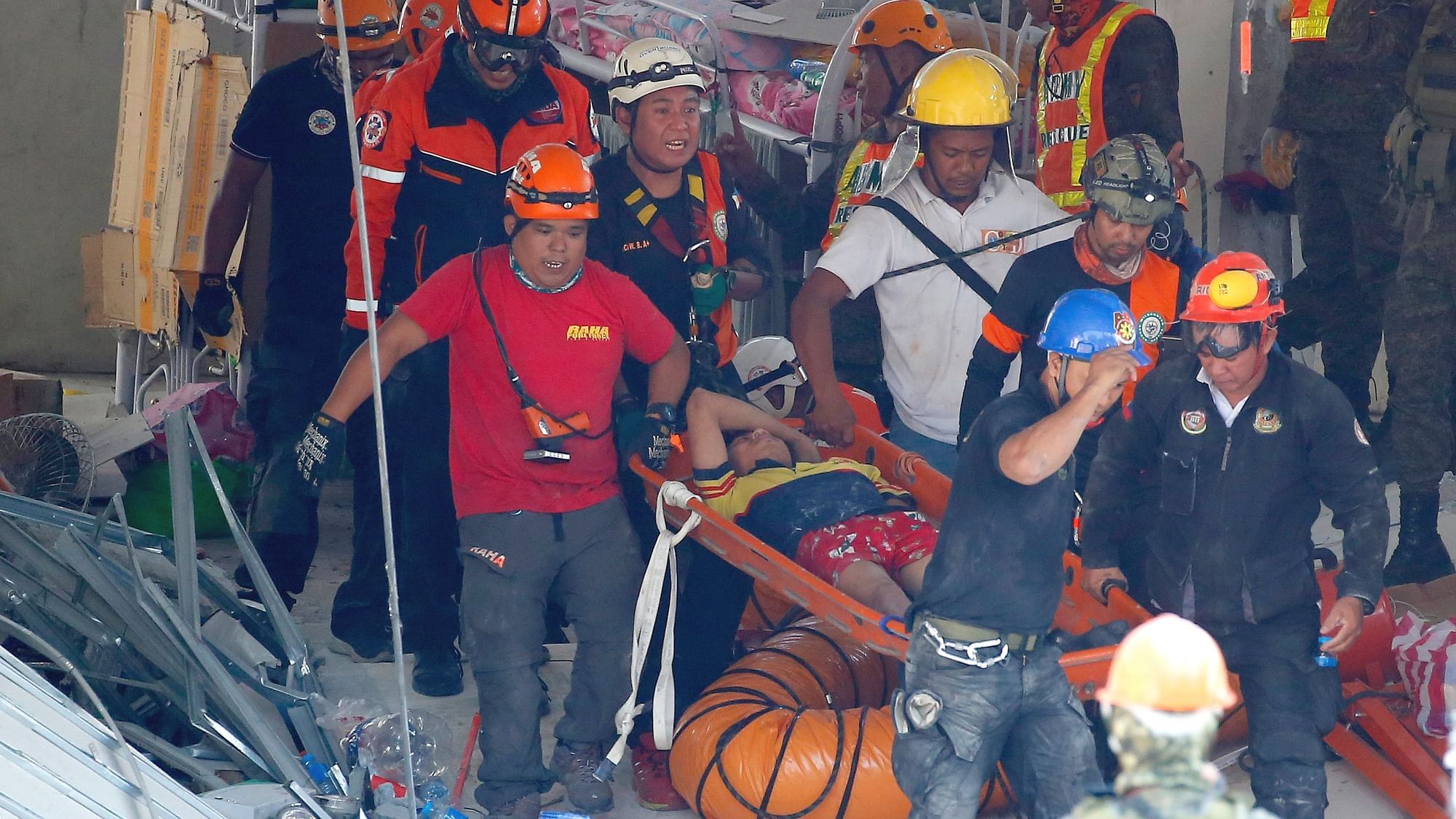 Rescuers carry an earthquake survivor after being pulled out from the rubble of a commercial building following a major earthquake in Porac township, Pampanga province, north of Manila, Philippines.
