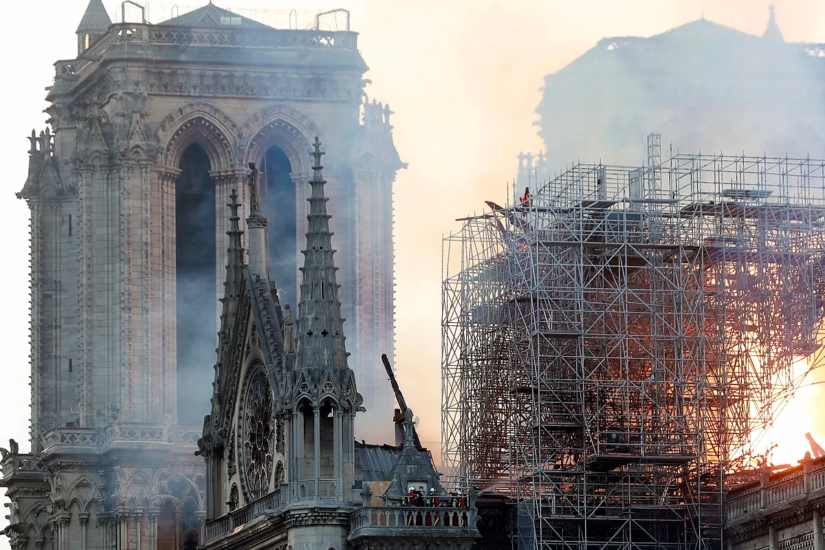 Massive plumes of yellow brown smoke is filling the air above Notre Dame Cathedral and ash is falling on tourists and others around the island that marks the center of Paris.