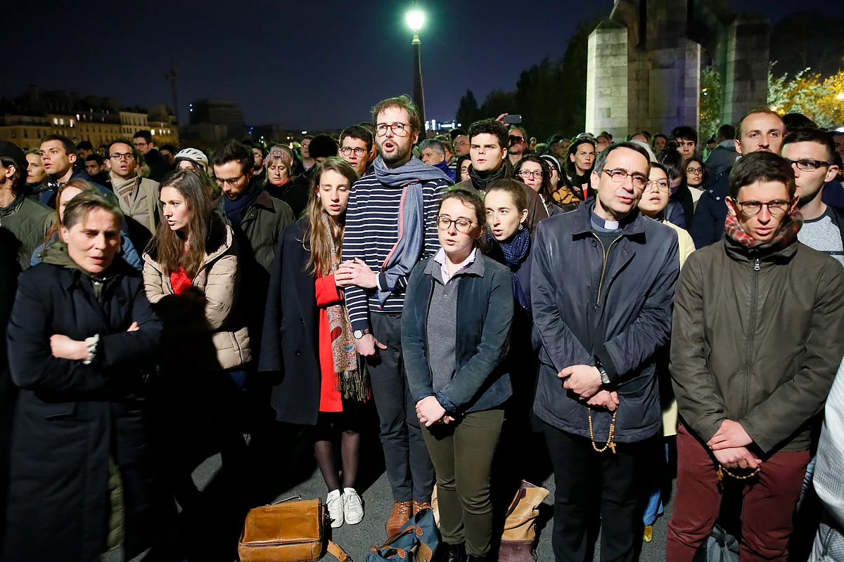 People pray as Notre Dame cathedral is burning in Paris, Monday, 15 April, 2019. 