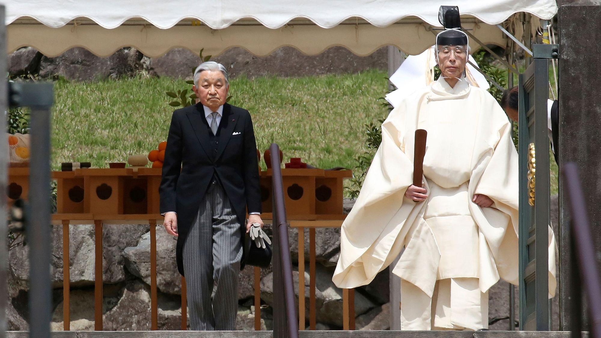 Japan’s Emperor Akihito, left, is led by a Shinto priest, after visiting the tomb of his late father Hirohito to report his retirement at the Musashino Imperial Mausoleum in Tokyo, Tuesday, 23 April 2019.