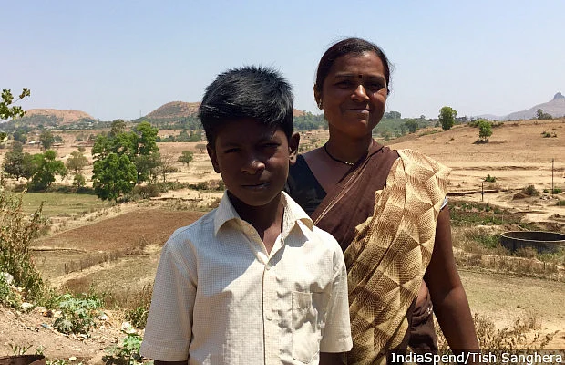 Kamal Gangrude, 35, with her son in Pimplad village of Maharashtra’s northwestern Nashik district. In the backdrop are the fields that used to provide a steady supply of farm jobs, but have now been sold to developers, thus restricting employment options for the village’s poor.