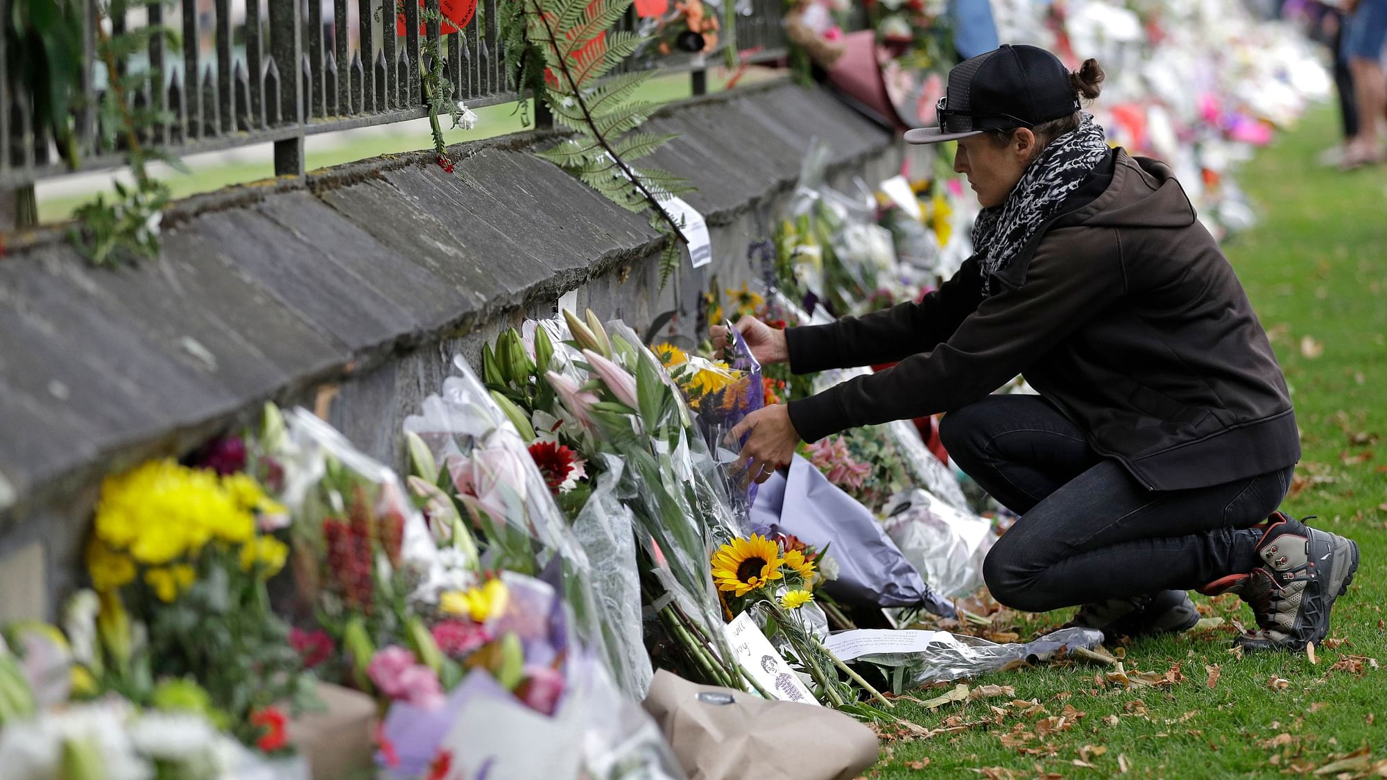 A woman pauses as she lays flowers on a wall at the Botanical Gardens, Christchurch. 