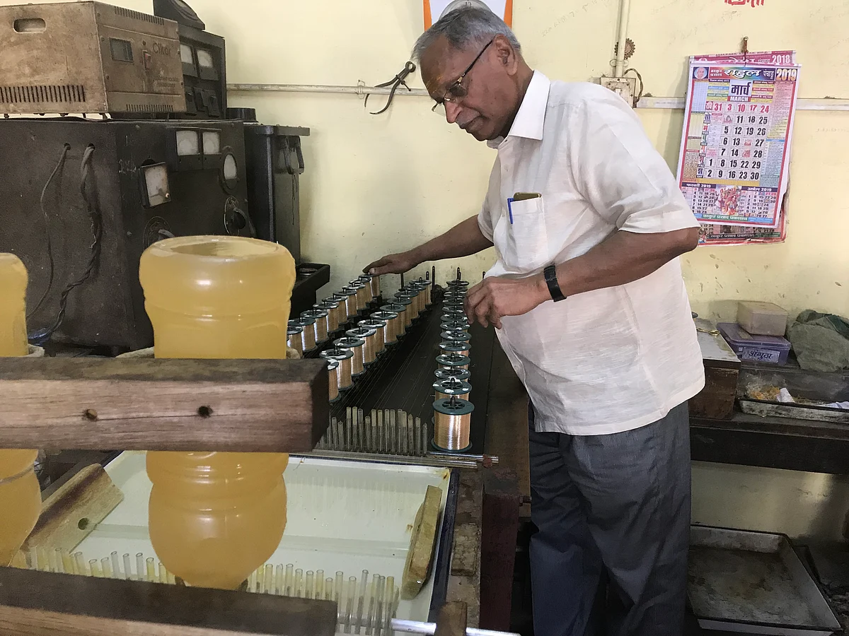 Shyam Sundar Jaiswal operating his machine that coats the silver thread with gold 