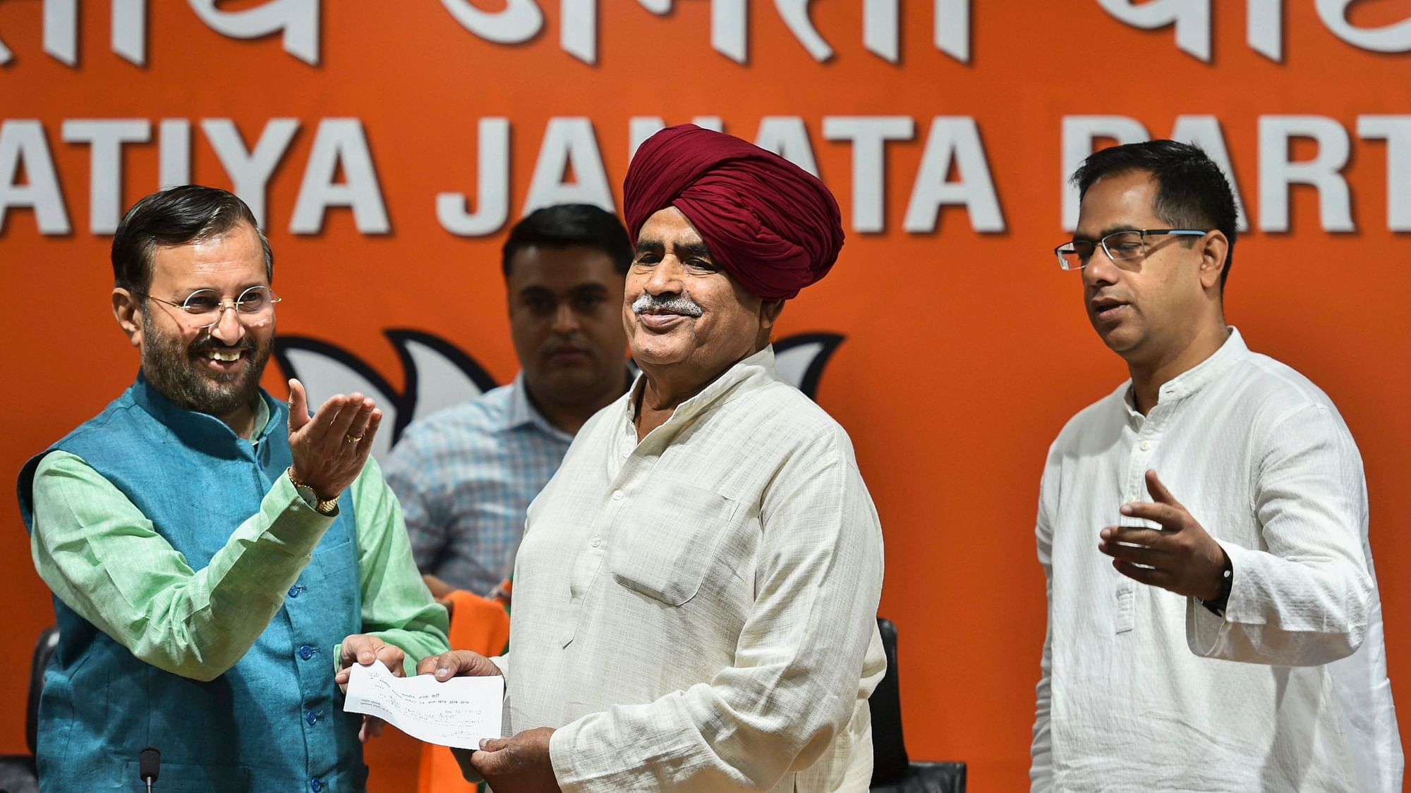 Union Minister and BJP leader Prakash Javadekar presents the membership slip to Gurjar Arakshan Sangharsh Samiti leader Kirori Singh Bainsla, as he joins BJP, ahead of Lok Sabha polls, in New Delhi, Wednesday, 10 April.