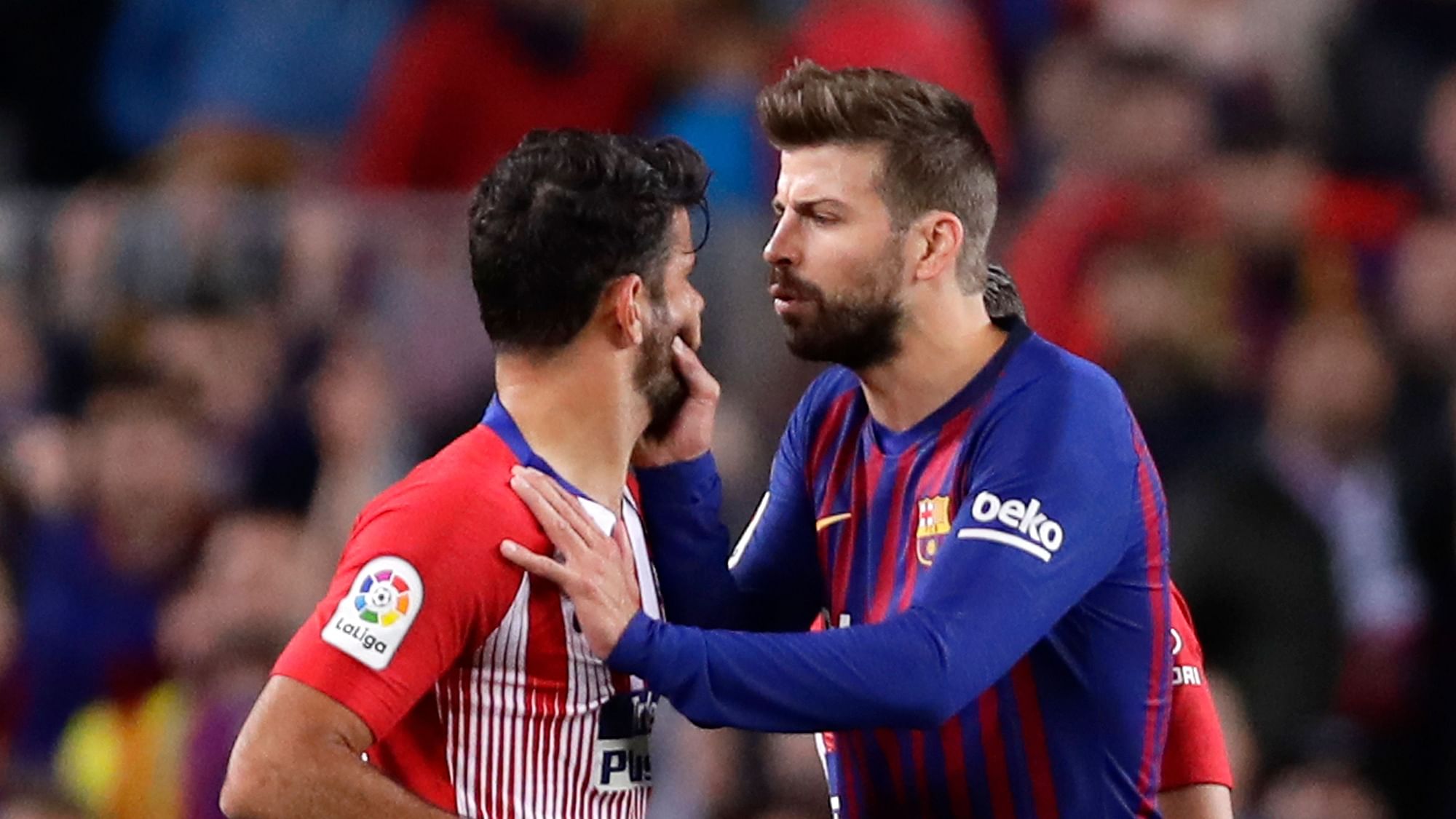 Barcelona’s Gerald Pique, right, talks to Atletico forward Diego Costa who was sent off with a red card for insulting referee Jesus Gil Manzano during a Spanish La Liga soccer.