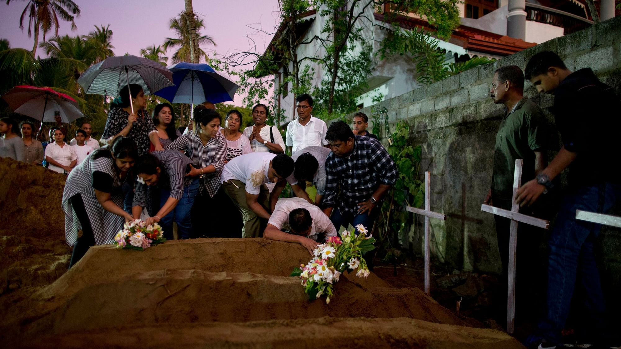 Relatives place flowers after the burial of three victims of the same family, who died during the Easter Sunday bomb blast at St Sebastian Church.