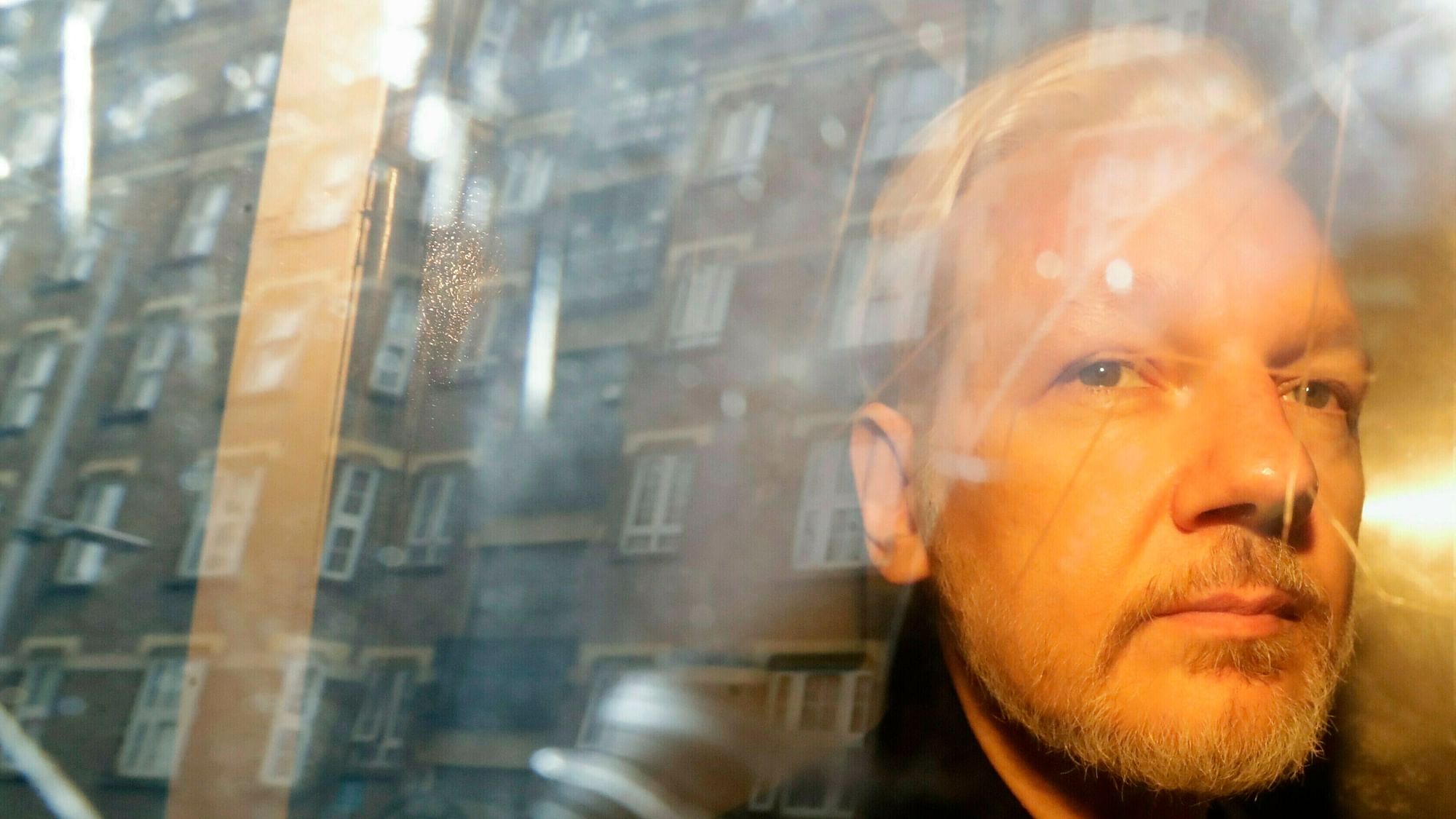  In this Wednesday, 1 May 2019 file photo, buildings are reflected in the window as WikiLeaks founder Julian Assange is taken from court.