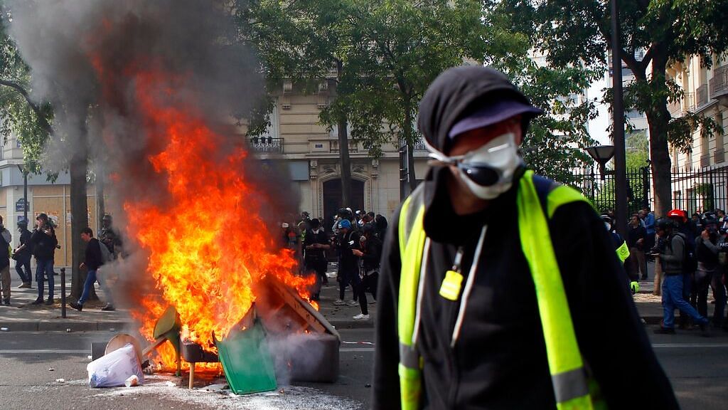 A man walks past garbage that was put on fire in Paris, Wednesday, 1 May 2019.&nbsp;