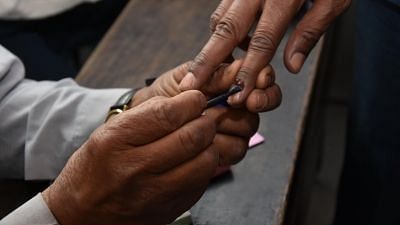 A polling official applies indelible phosphorus ink on the fore finger of a voter.