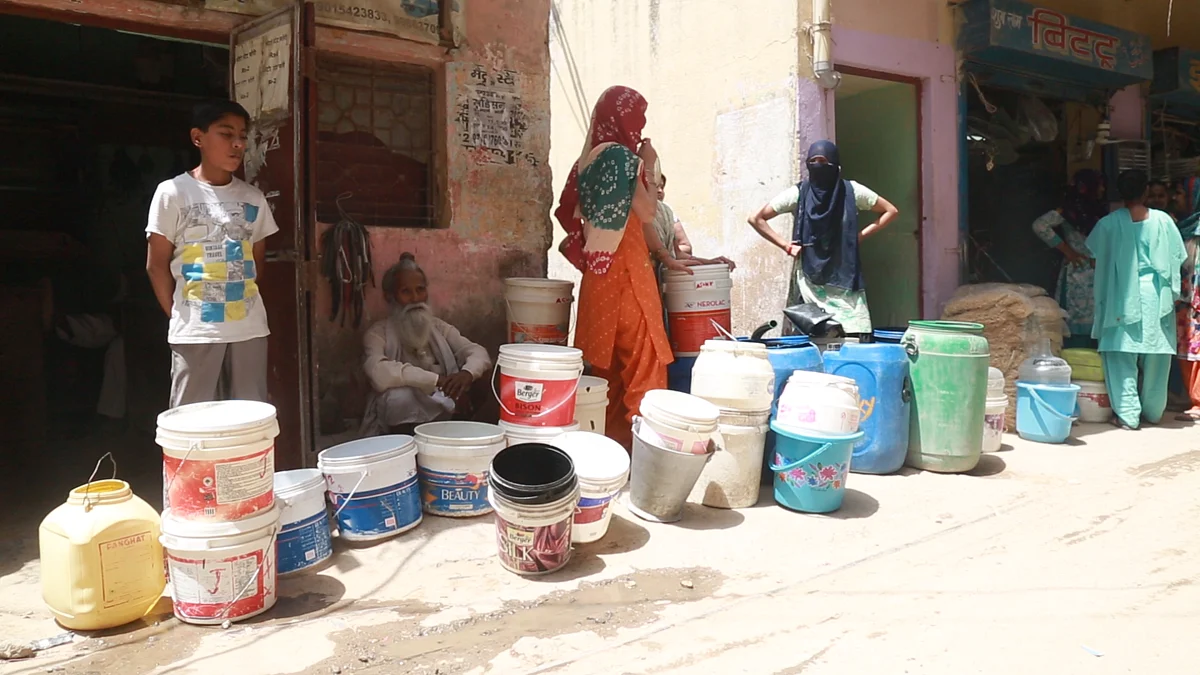Women wait in the heat to fill water from the water tanker. 