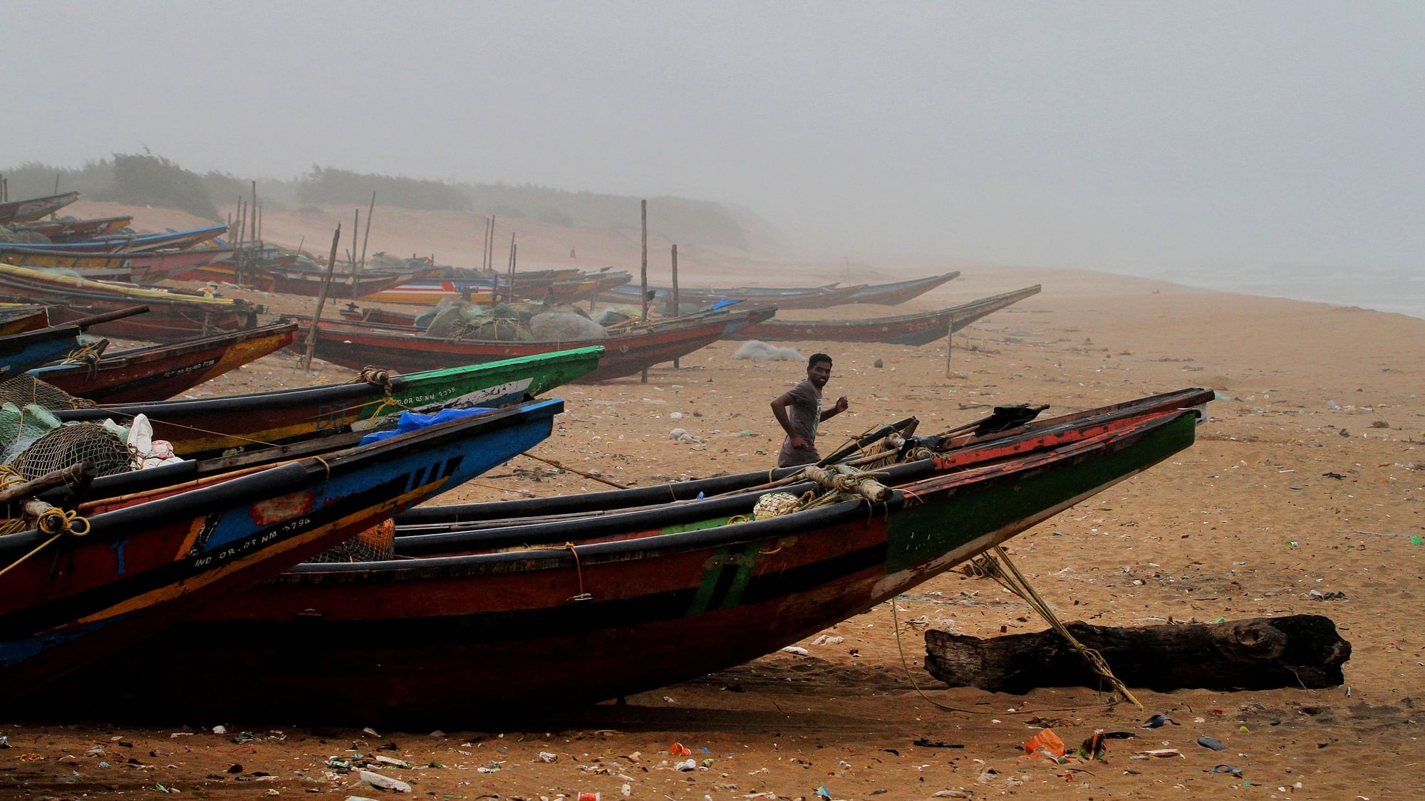 A fisherman runs between the docked fishing boats amid strong winds at in Puri, Odisha, on 2 May.
