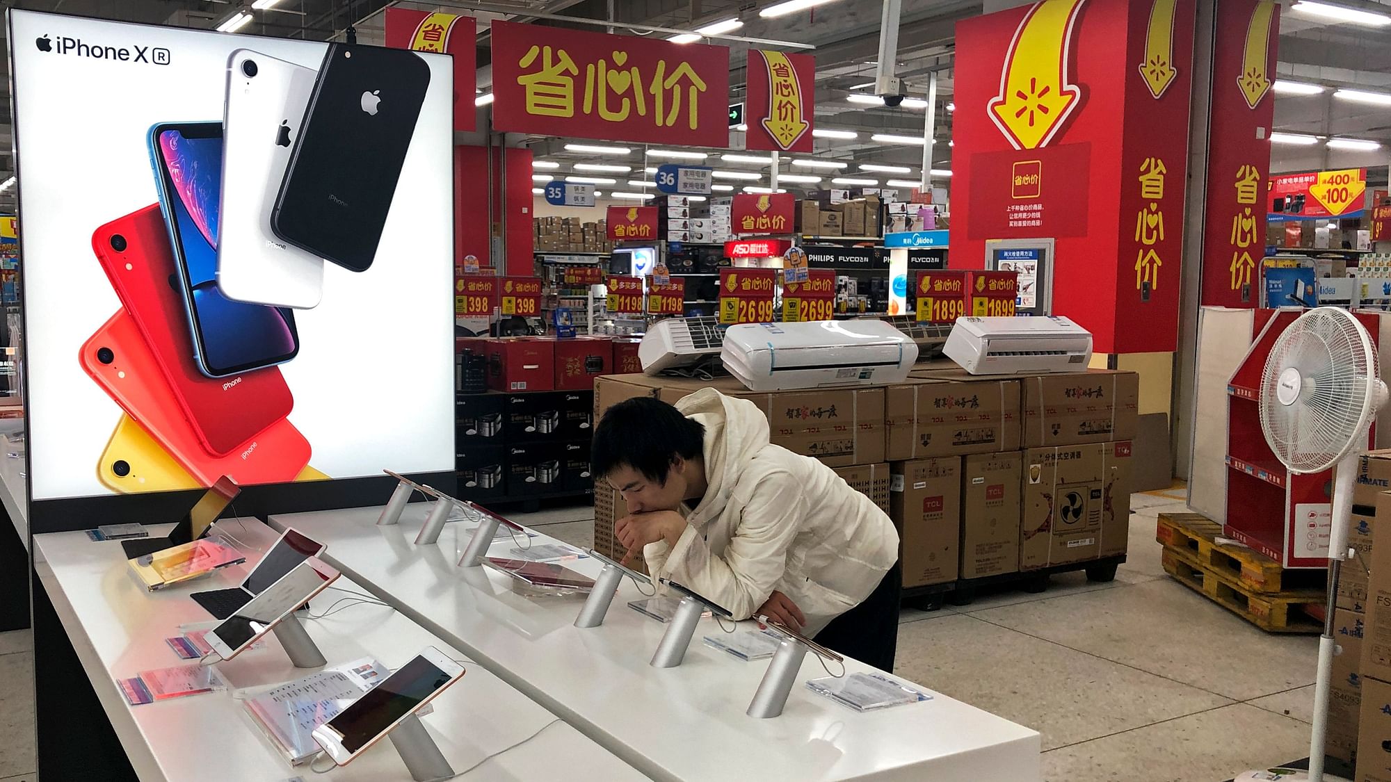 A man browses an iPhone unit on display at a section selling Apple’s products together with Chinese made electric appliances at a hypermarket in Beijing.