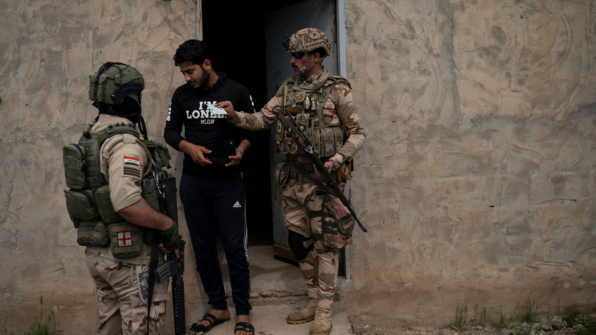 Iraqi army 20th division soldiers check the ID of a man during a raid in Badoush, Iraq.