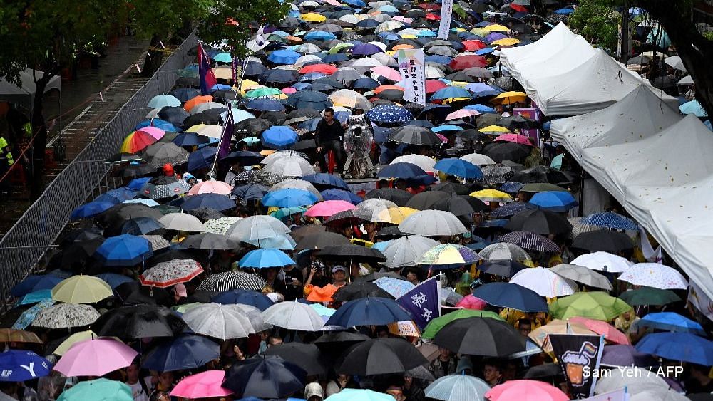 Taiwan gay rights supporters wait in the rain outside parliament in Taipei for the results of a vote on same-sex marriage.