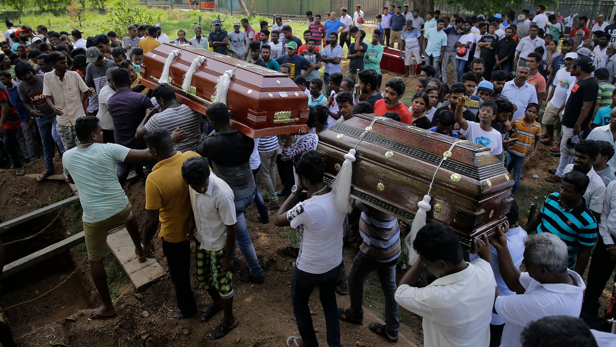 Sri Lankans carry coffins bearing the remains of Berington Joseph, left, and Burlington Bevon, right, who were killed in the Easter Sunday bombings in Colombo, Sri Lanka.
