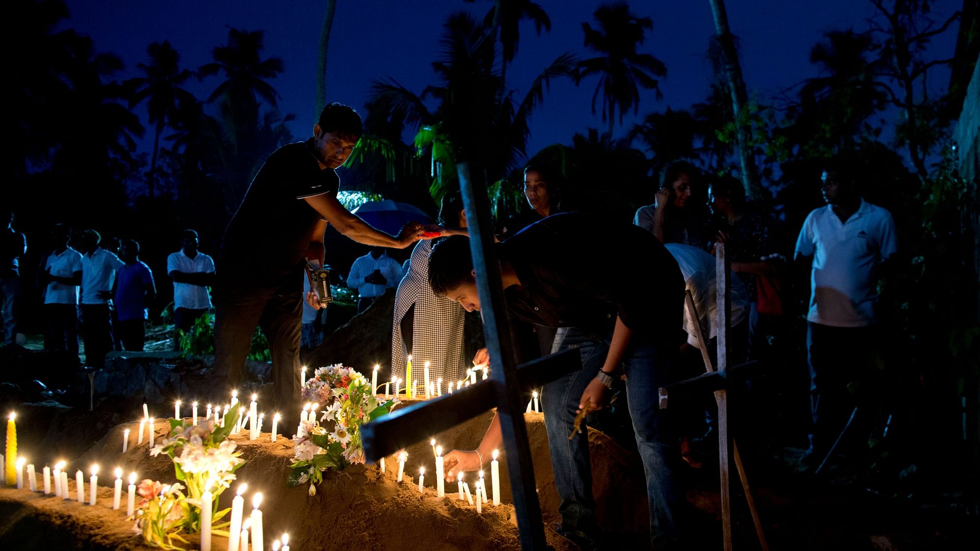 Relatives light candles after the burial of three victims of the same family, who died at Easter Sunday bomb blast at St Sebastian Church in Negombo, Sri Lanka.