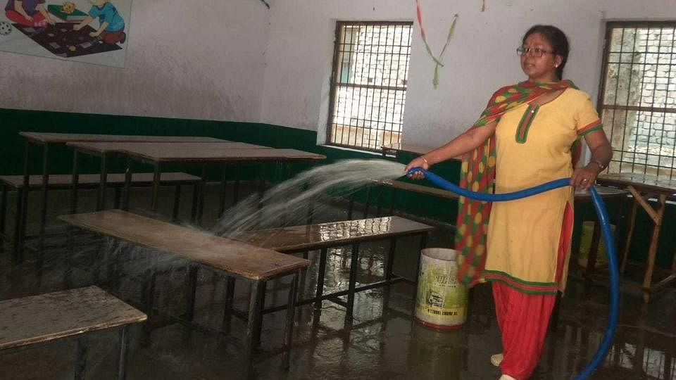 A teacher in primary school (boys) in North Vijay Nagar Colony, Agra, cleaning a classroom