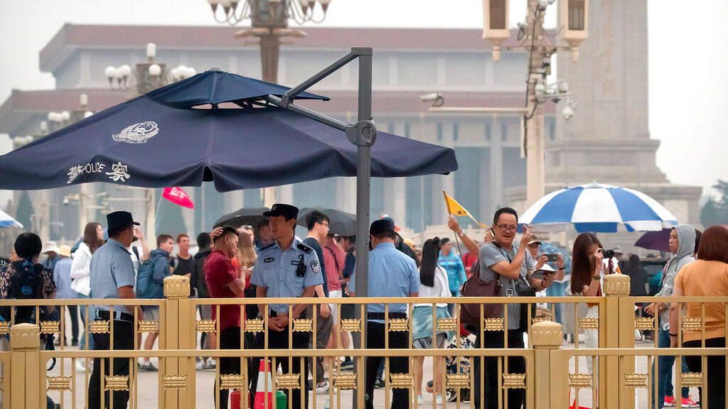 Security officials stand guard as tourists take photos on Tiananmen Square in Beijing, Tuesday, June 4, 2019. 