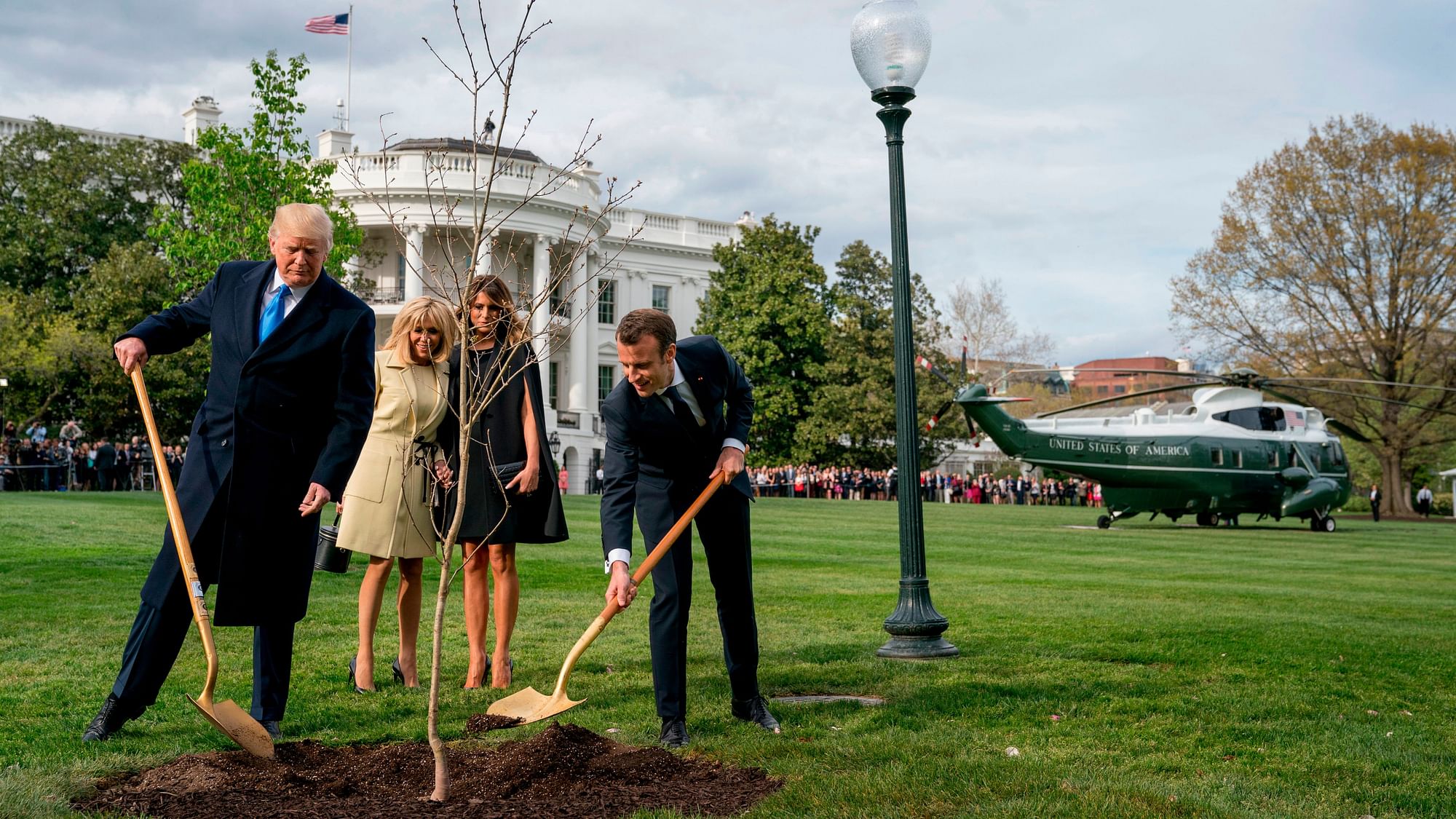 In this 23 April, 2018 file photo, Melania Trump, second right, and Brigitte Macron, second left, watch as President Donald Trump and French President Emmanuel Macron participate in a tree planting ceremony on the South Lawn of the White House in Washington.
