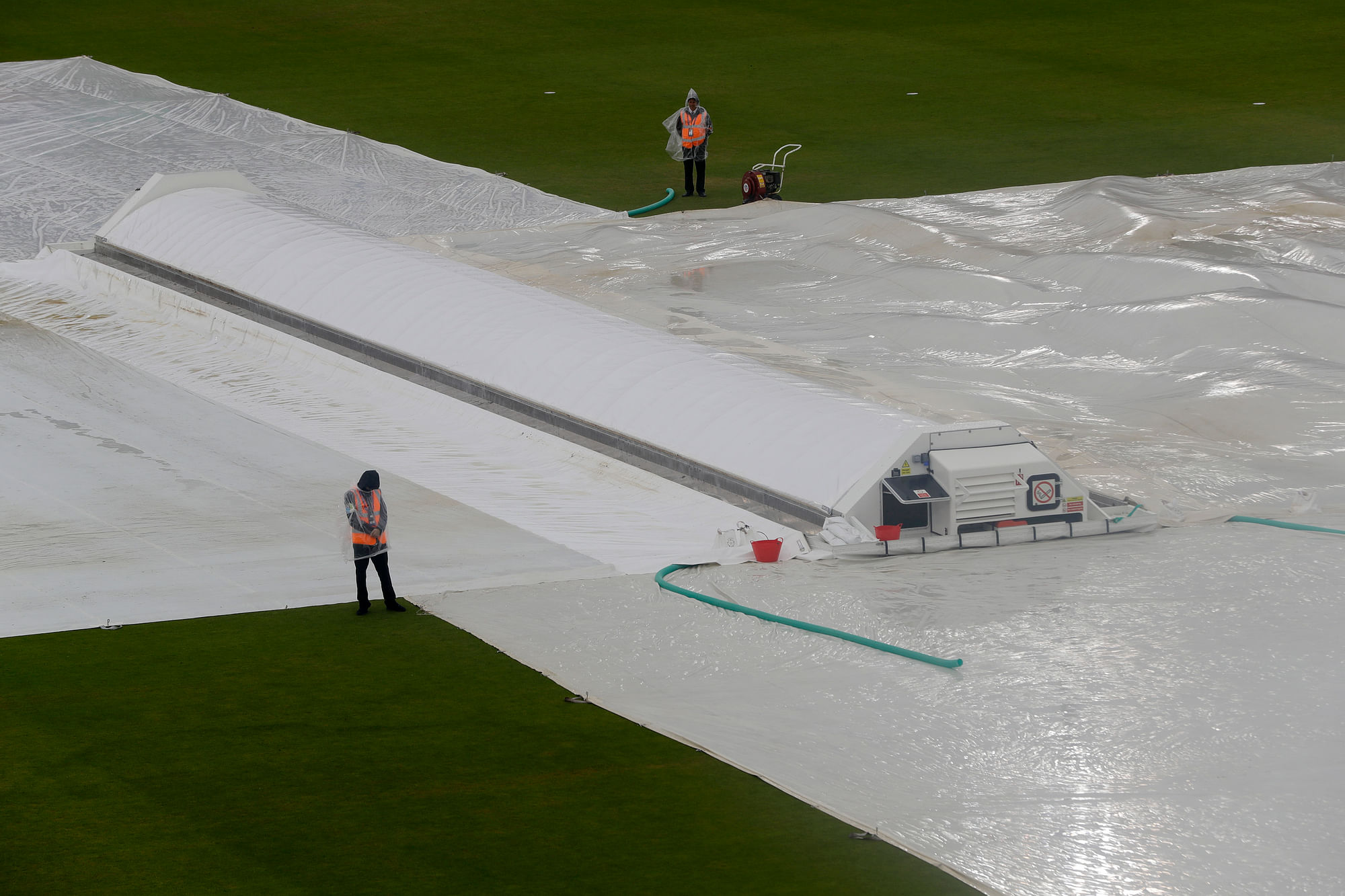 File: Stewards stand alongside rain covers on the pitch after play was stopped due to rain during the World Cup cricket match between South Africa and the West Indies at The Ageas Bowl in Southampton.