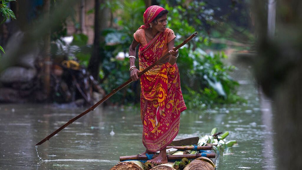 A woman rows a makeshift banana raft through flood waters in Burgaon in Assam, on Monday, 15 July 2019.&nbsp;