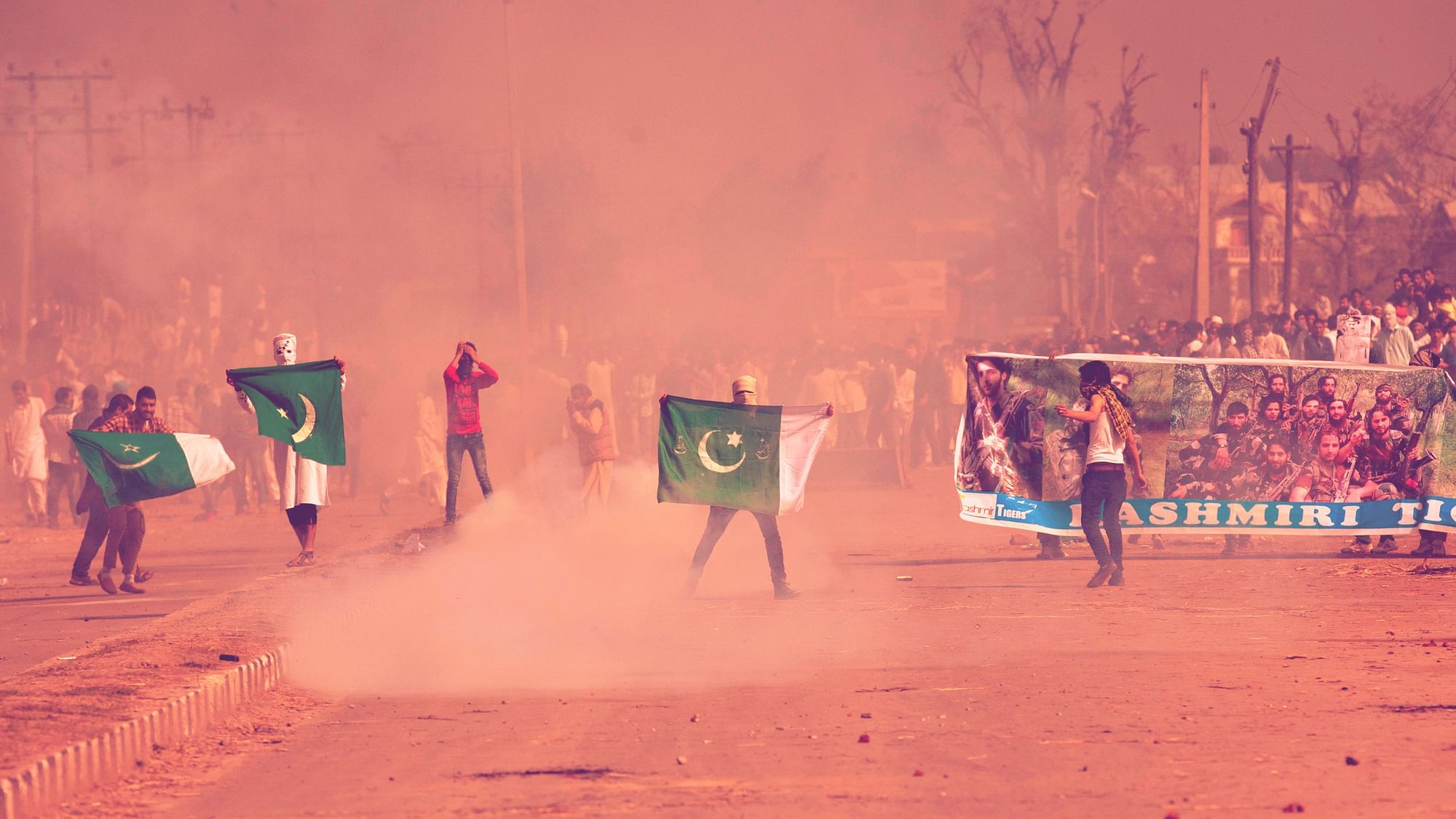  Masked Kashmiris hold the national flag of Pakistan and a banner displaying militant leaders of the Hizb-ul Mujahedeen during a protest.&nbsp;