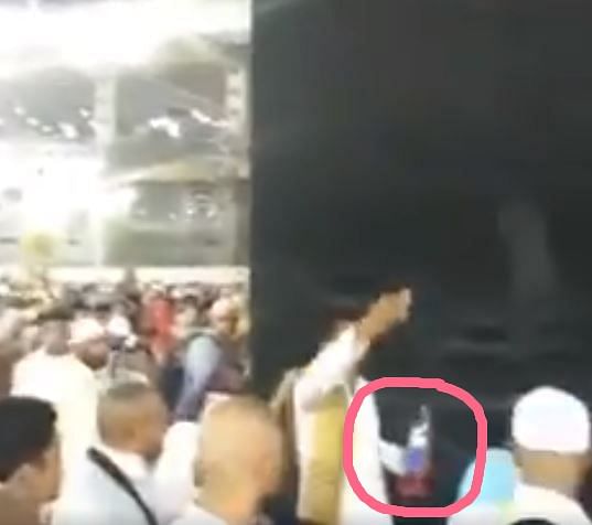 The man can be seen pouring a liquid on the cloth which covers the Kaaba and then shouting something in Arabic.