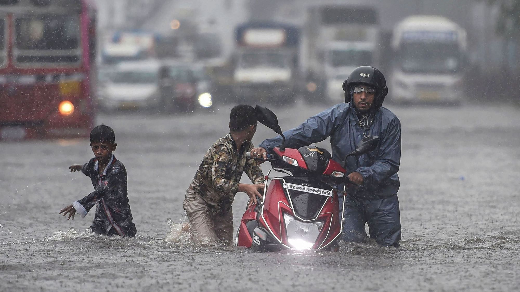 Commuters wade through a waterlogged street during heavy monsoon rain in Mumbai’s Ghatkopar  on Tuesday, 2 July.