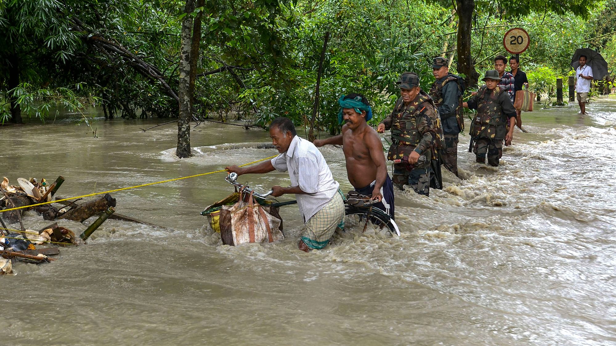 Army personnel help villagers cross a flooded street following monsoon rainfall at Dhamdhama in Nalbari district of Assam on 24 July 2019. &nbsp;