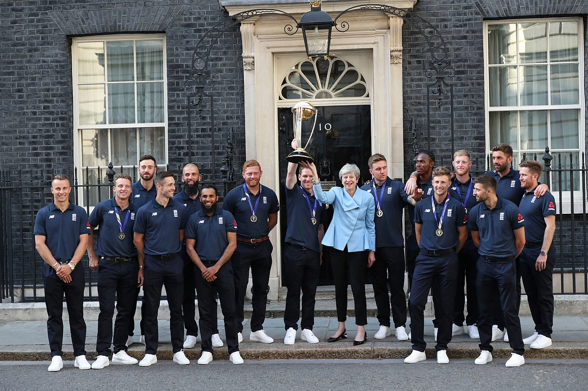 Britain’s Prime Minister Theresa May smiles as she stands with England cricket captain Eoin Morgan, members of the team and the trophy after England won the Cricket World Cup, outside Downing Street in London.