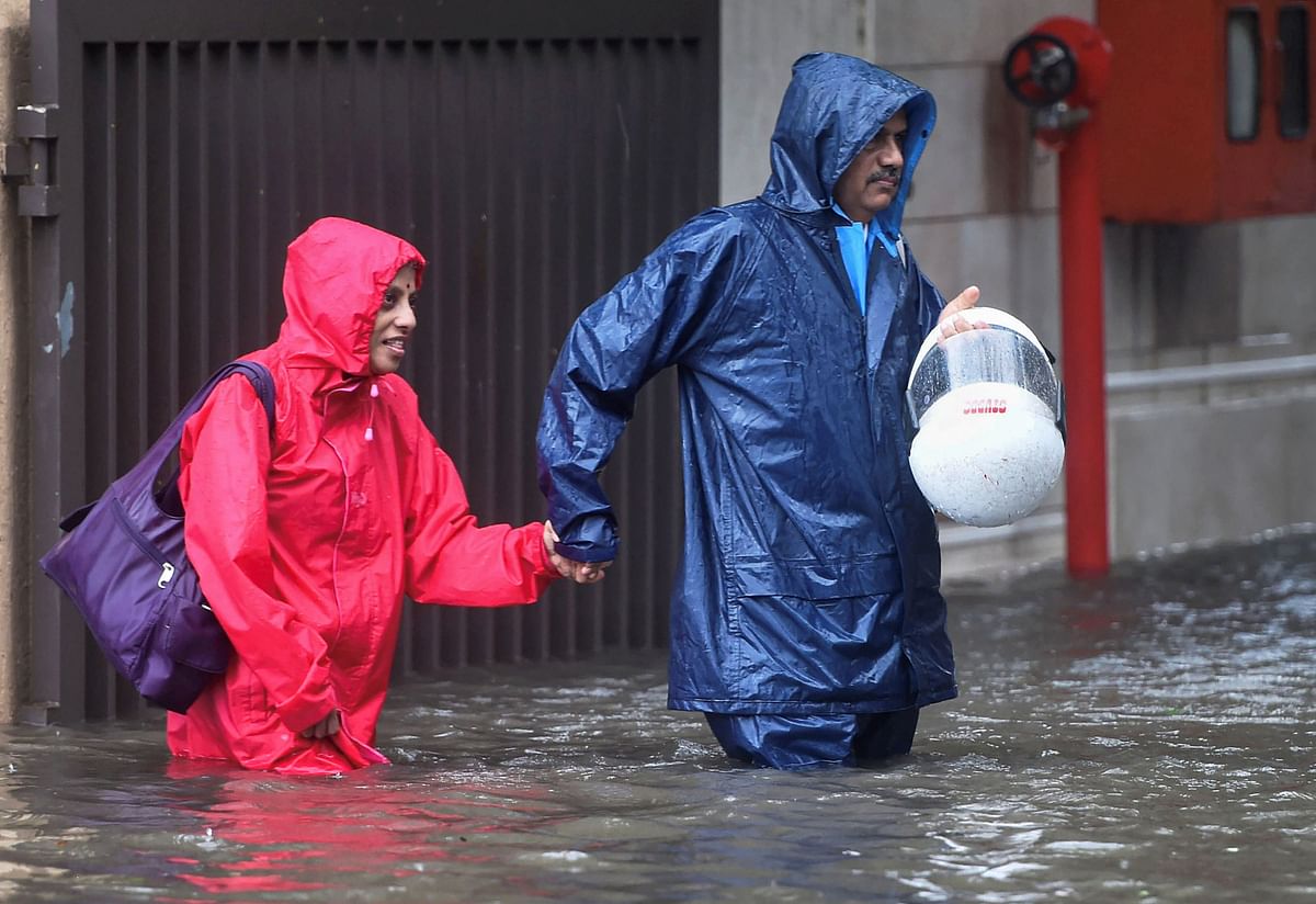 Pedestrians wade through a waterlogged street during monsoon rain.