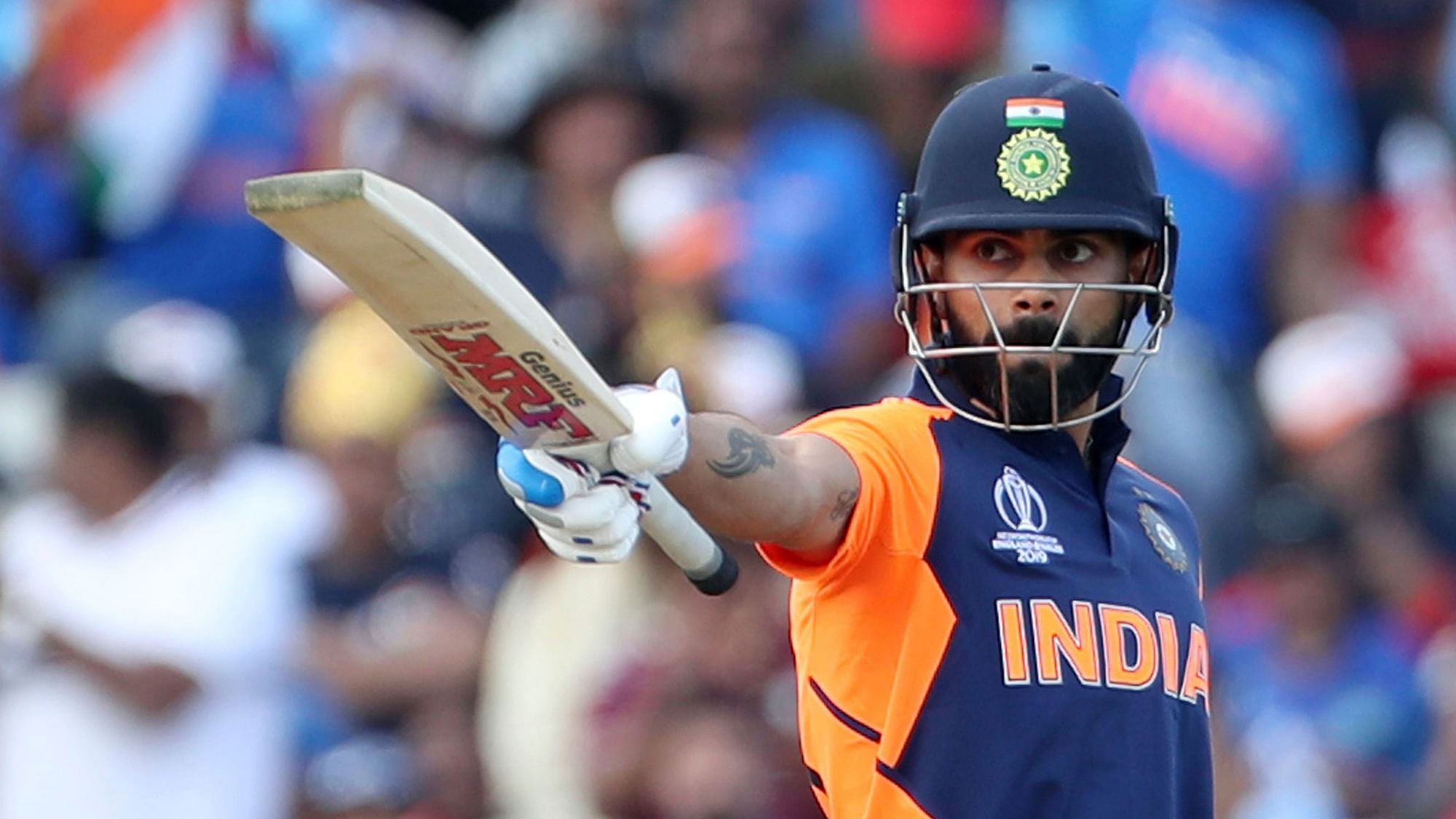 India’s captain Virat Kohli raises his bat to celebrate scoring fifty runs during the Cricket World Cup match between England and India