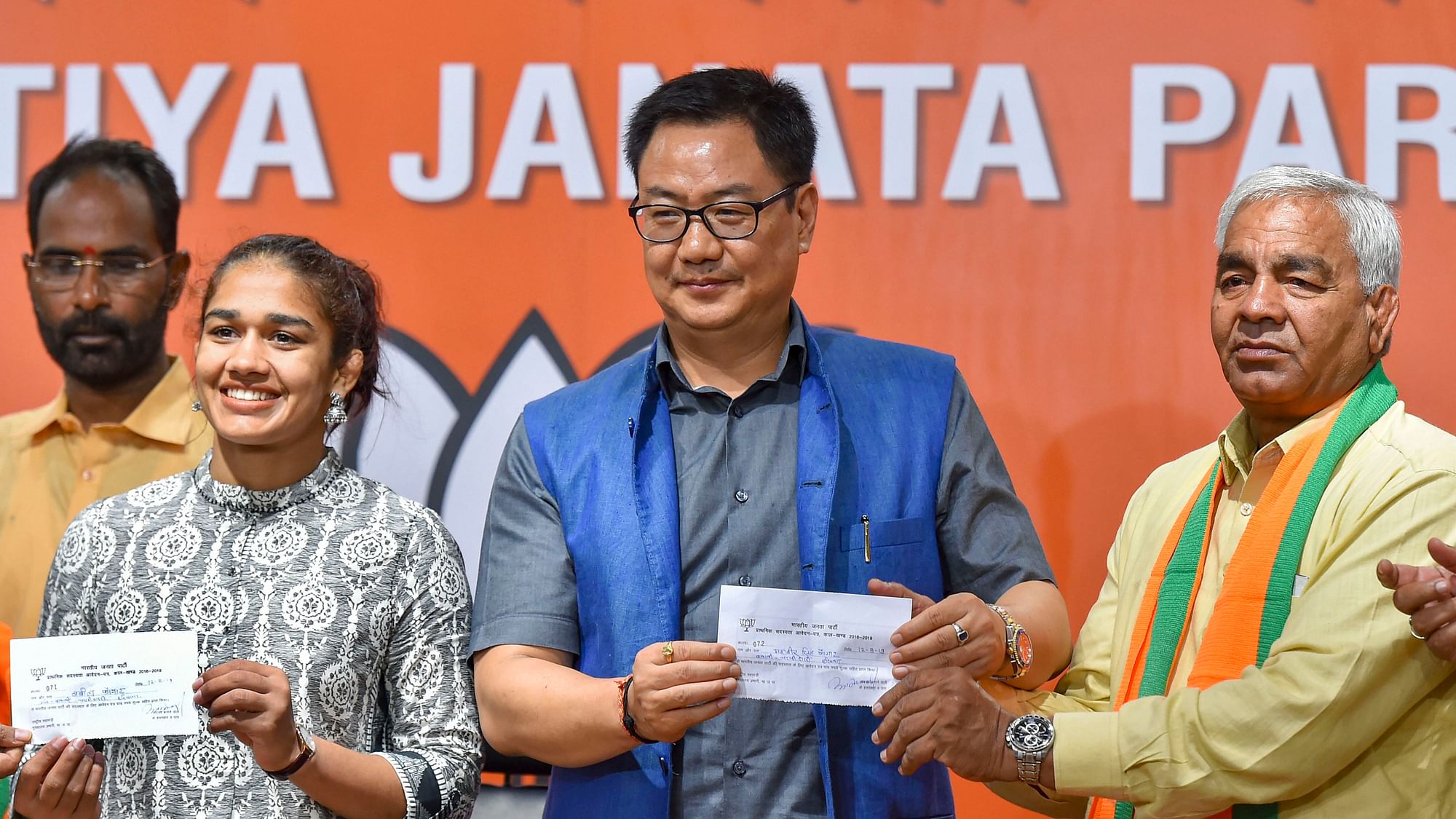 Union Minister Kiren Rijiju offers membership slip to wrestler Babita Phogat and her father Mahavir Singh Phogat as they join the BJP at party headquarters  in New Delhi.&nbsp;