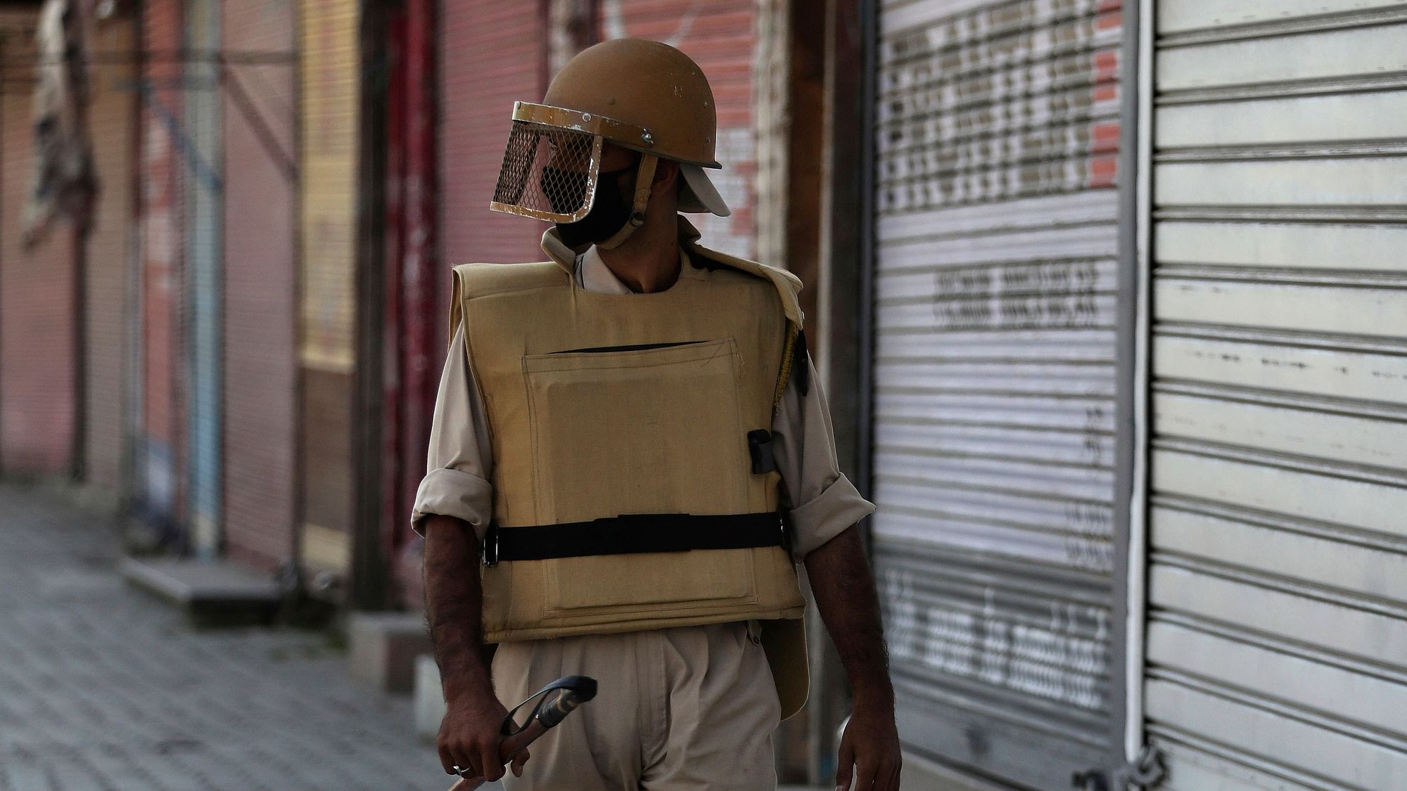 Kashmiri policeman guards outside a closed shop in Srinagar, Kashmir.